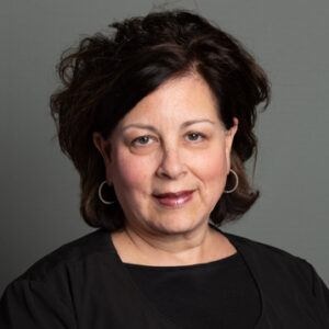 Experienced Orthodontic Insurance Coordinator, Robyn, smiling in a black shirt and cardigan