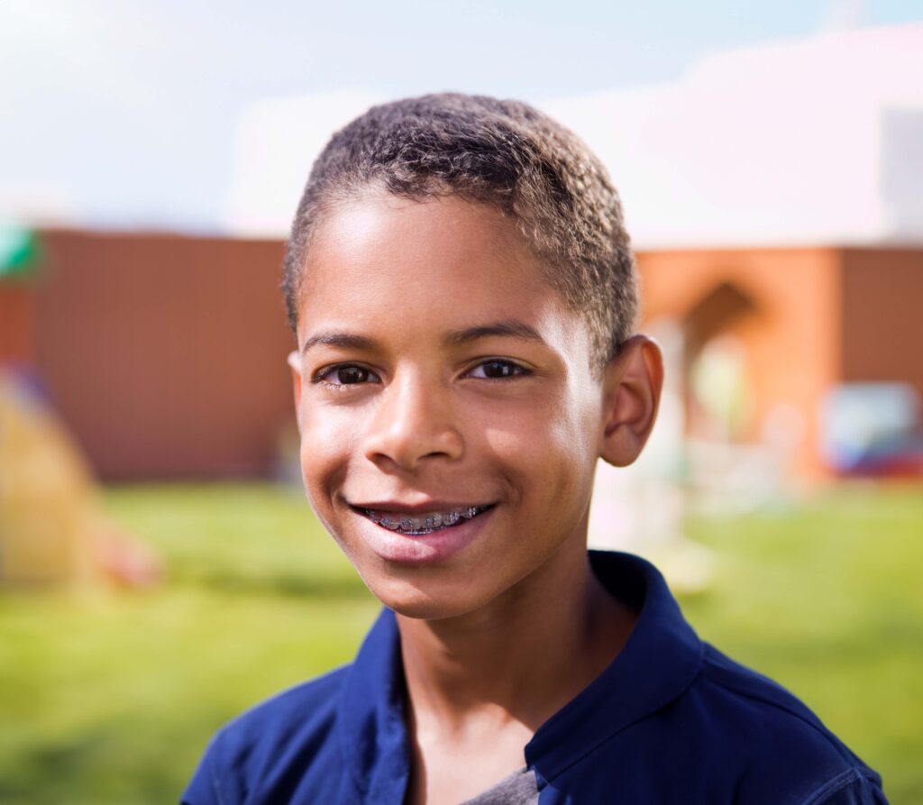 Adorable boy with braces for kids smiling in a park