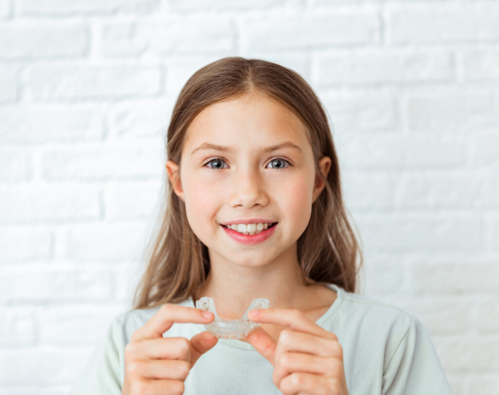 Young girl with Invisalign First holding her aligner with both hands